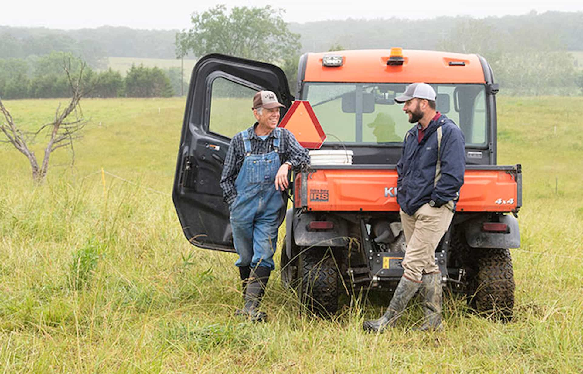 two mean talking near farm equipment